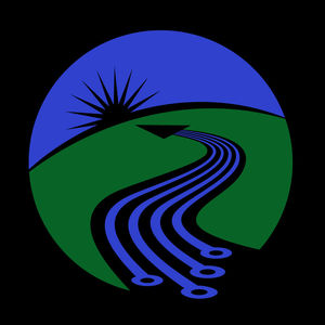 Circular illustration on a black background with lines referencing circuit board elements reminiscent of farmland furrows, winding a path through green space to their endpoint as an arrow near a horizon, pointing to a rising sun in blue sky