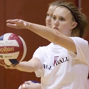 Female player holds volleyball in front of her in preparation to serve