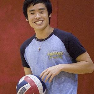 A boy holds a volleyball and smiles