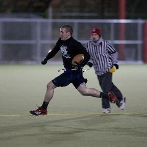 A player with the ball runs down the field with a referee behind him