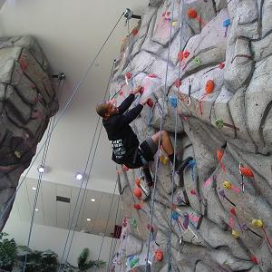 A man hangs back while climbing up the rock wall