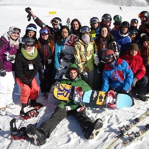 Snowboarders pose together in the snow during a trip