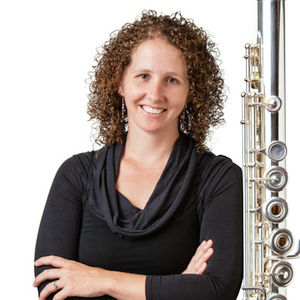 Photo of woman with curly hair and arms crossed with a flute along the right side.