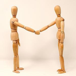 2 wooden sketch figures shaking hands