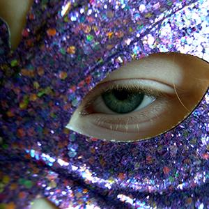 Eye looking through a glitter mask