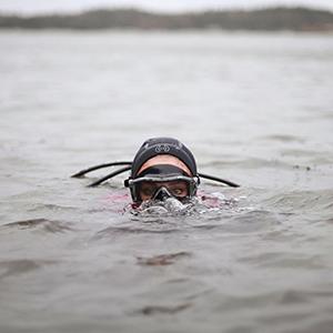 Scuba diver with just her eyes above water in a still from Hope Ginsburgs "Breathing on Land: Bay of Fundy"