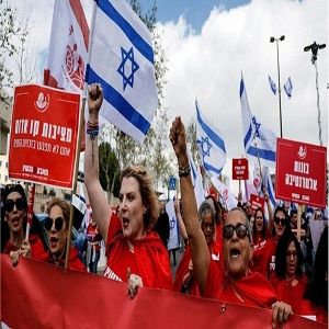 Israeli women protesters wearing red shirts and holding signs and the Israeli flag