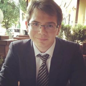 image of Ivan wearing glasses, in a suit sitting at a table 