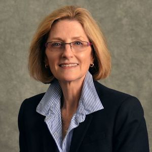 image of Holly Mayer, wearing glasses, in a blue shirt and black blazer