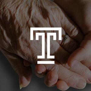 The hand of a Personal Care Home Administrator clasped in the hand of an elderly patient. with the Temple University emblem superimposed.
