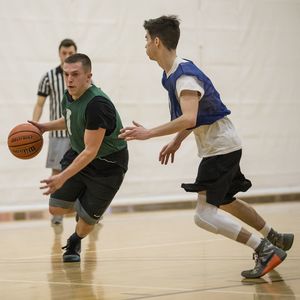 A basketball player tries to dribble past the defender guarding him.