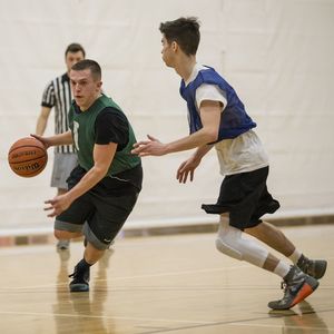 A basketball player attempts to dribble past a defender.