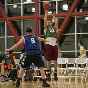 An intramural basketball player shoots a 3 point shot over the defender guarding him.