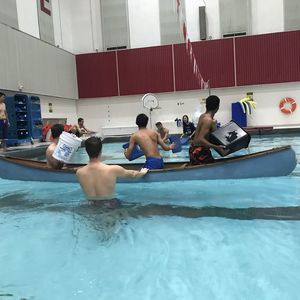 Two teams in canoes throw buckets of water at each other in an attempt to sink their opponents canoe.