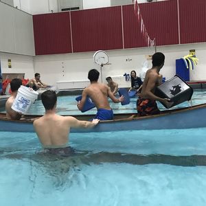 Two canoes of competitors throw water at each other trying to sink the opposing canoe.