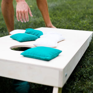 A photo of a cornhole board with bean bags sitting on it.