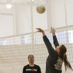 A player setting a volleyball for a teammate.