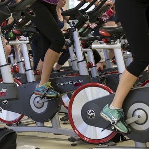 Shots of the lower half of stationary bikes during a group fitness cycling session.