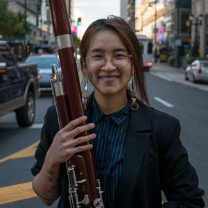 headshot of woman in a dark blazer and pinstripe shirt holding a bassoon, standing in a city street