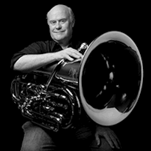 black and white photo of a man sitting with a tuba in his lap