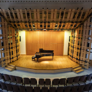 rock hall auditorium with a piano centered on a lit stage