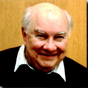 headshot of a balding man with white hair and a black sweater