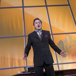 man in a suit singing in front of a yellow painted backdrop