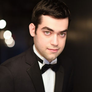 headshot of man with short black hair and a tuxedo